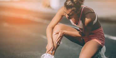 Eine Frau hat Schmerzen nach einer Verletzung und braucht erste Hilfe im Sport.