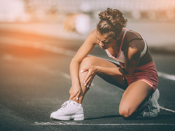 Eine Frau hat Schmerzen nach einer Verletzung und braucht erste Hilfe im Sport.